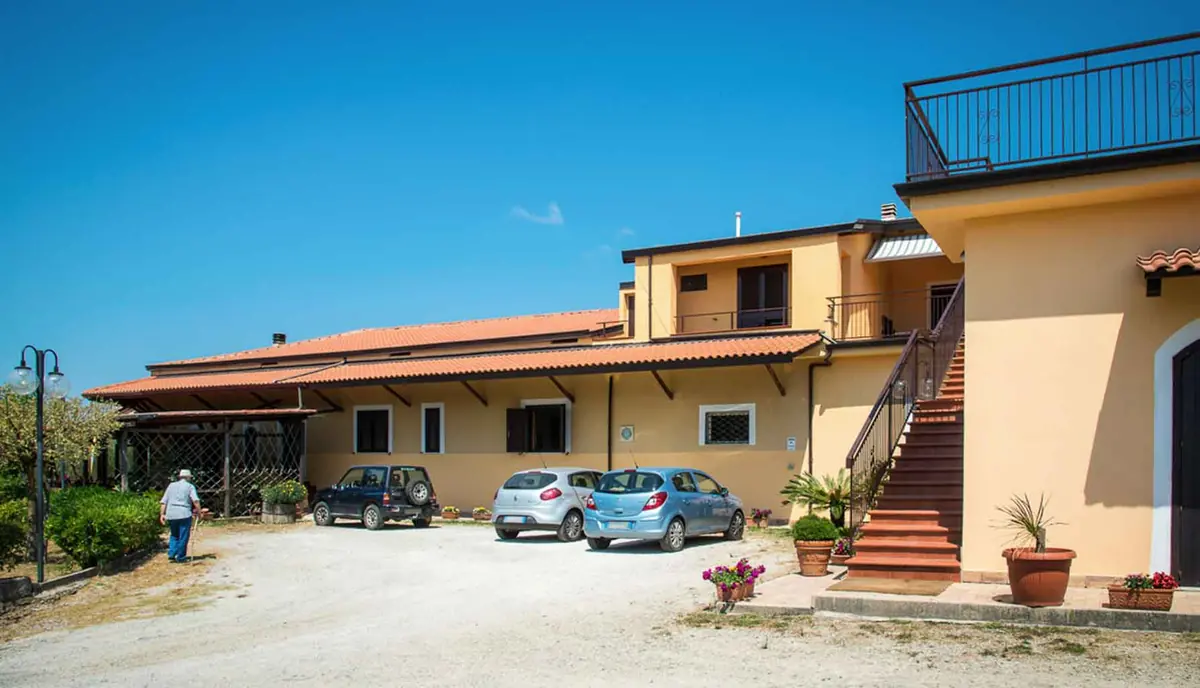 La facciata dell'agriturismo con la scala esterna e le auto nel piazzale