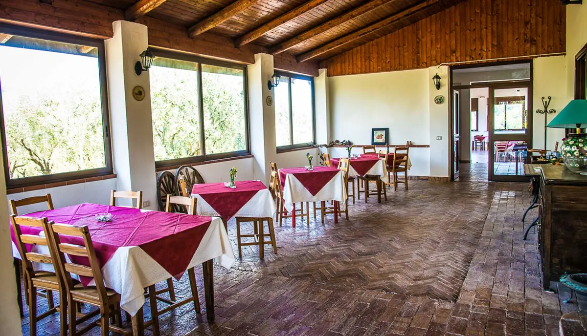 Sala del ristorante con tavoli apparecchiati e travi di legno
